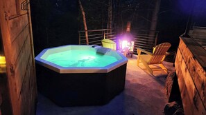 Ein Whirlpool in einer Holzhütte mit einem Stuhl und einer Laterne.