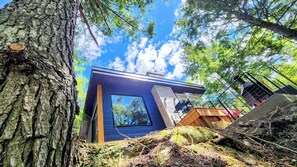 A modern treehouse with a large window, surrounded by forest. - Spa & Sauna | Plume Boreale (Saint-Alexis-des-Monts)