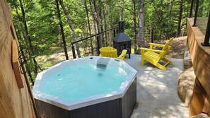 Een hottub omringd door een houten terras, met een schoorsteen en een gele stoel op de achtergrond.