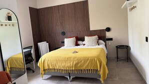 A modern bedroom with a bed, a mirror, a bedside table, and a small stool. - PONIENTE BEACH HOUSE New Luxury independent villa 4suite bedroom NovoSancti Petr (Chiclana de la Frontera)