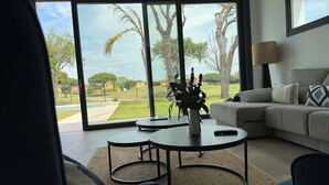 A modern living room with a large sliding glass door leading to a backyard, a round coffee table, a sofa, and a lamp. - PONIENTE BEACH HOUSE New Luxury independent villa 4suite bedroom NovoSancti Petr (Chiclana de la Frontera)