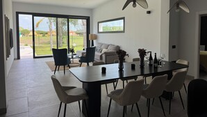 A modern dining area with a large table, chairs, and pendant lights. - PONIENTE BEACH HOUSE New Luxury independent villa 4suite bedroom NovoSancti Petr (Chiclana de la Frontera)