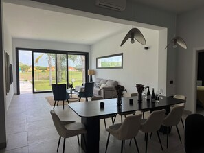 A modern dining area with a large table, chairs, and pendant lights. - PONIENTE BEACH HOUSE New Luxury independent villa 4suite bedroom NovoSancti Petr (Chiclana de la Frontera)