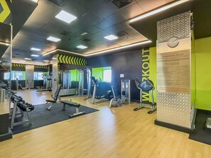Ein Fitnessraum mit Trainingsgeräten, Spiegeln und einer Wand mit Regeln für das Fitnessstudio.