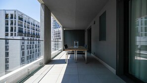 Ein Balkon mit Tisch und Stühlen, einem Blumentopf und Blick auf moderne Gebäude.