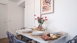 Ein Esstisch mit Tellern, Gläsern, einer Blumenvase und einer Käseplatte.