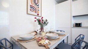 Ein Esstisch ist gedeckt mit Tellern, Gläsern, einer Blumenvase und einer Käseplatte.