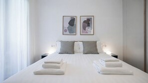 Ein Hotelzimmer mit einem ordentlich bezogenen Bett, zwei Nachttischen mit Lampen und abstrakter Kunst an der Wand.