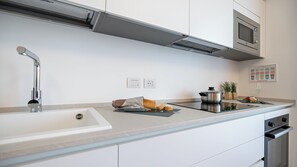 Eine moderne Küche mit Spüle aus Edelstahl, einer Mikrowelle und einem Backofen. An der Wand befinden sich zwei Steckdosen.
