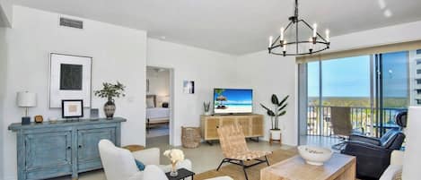 Una sala de estar moderna con televisión, asientos, un comedor y vistas al exterior.
