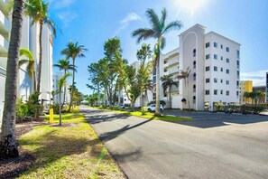 A street lined with palm trees and a white building with balconies. - Casa Marina 644 - Bay View (Fort Myers Beach)