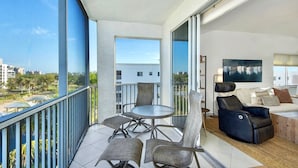 Ein Balkon mit Esstisch und St ühlen, einer Couch und einem Fernseher.