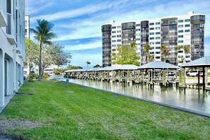 A waterfront hotel with outdoor seating areas, a pool, and modern buildings in the background. - Casa Marina 644 - Bay View (Fort Myers Beach)