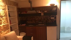 Ett kompakt bostadsutrymme med en soffa, ett litet kök och utsikt över omgivningen.