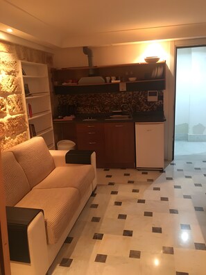 A compact living space with a sofa, kitchenette, and a view of the outside. - 'Centro Casa 2' Studio Apartment – Ideal for Short Stays (Palermo)