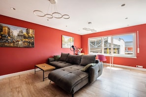 A modern living room with a sectional sofa, a small table, and two paintings on the wall.