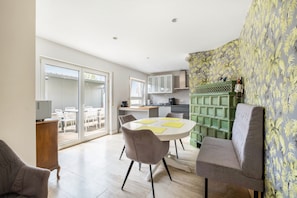 A modern kitchen with white cabinets, a dining area with a round table, and a sliding glass door leading to an outdoor patio.
