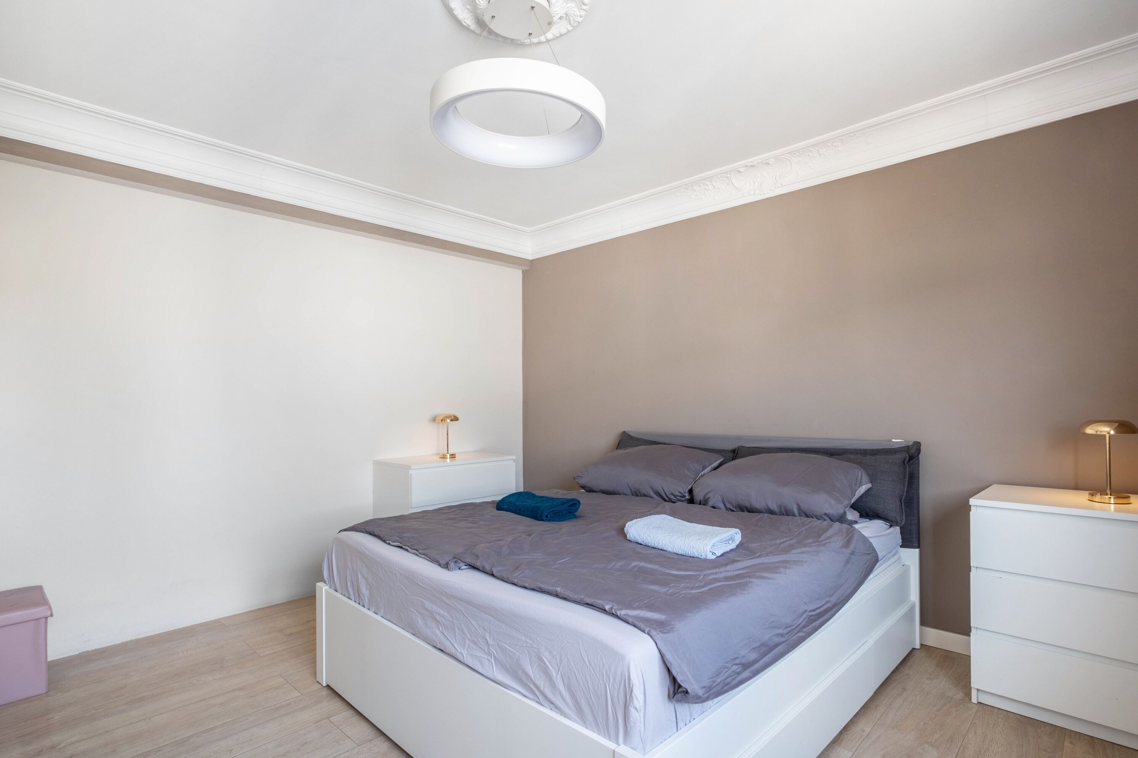 A bedroom with a bed, bedside tables, and a ceiling light fixture.
