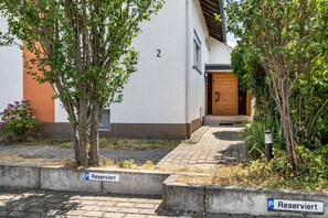 Ein Gebäude mit weißer Fassade, einer nummerierten Tür und einem gepflasterten Eingang.