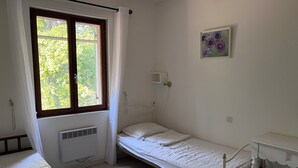 A single-bed room with a window, a bedside table, a wall-mounted light, and a small painting. - The House Across the Street: A Provençal villa with a pool and air conditioning in Lacoste. (Lacoste)