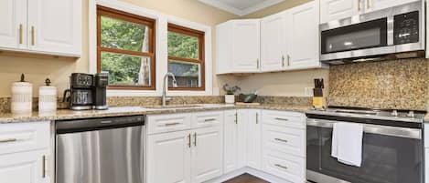 A modern kitchen with white cabinets, stainless steel appliances, and a granite countertop.