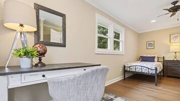 A bedroom with a desk, chair, bed, and a window.