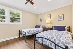 A bedroom with two beds, a ceiling fan, a window with a view, and a nightstand with a lamp. - Renovated 3BR near Lake Keowee & Clemson (Seneca)