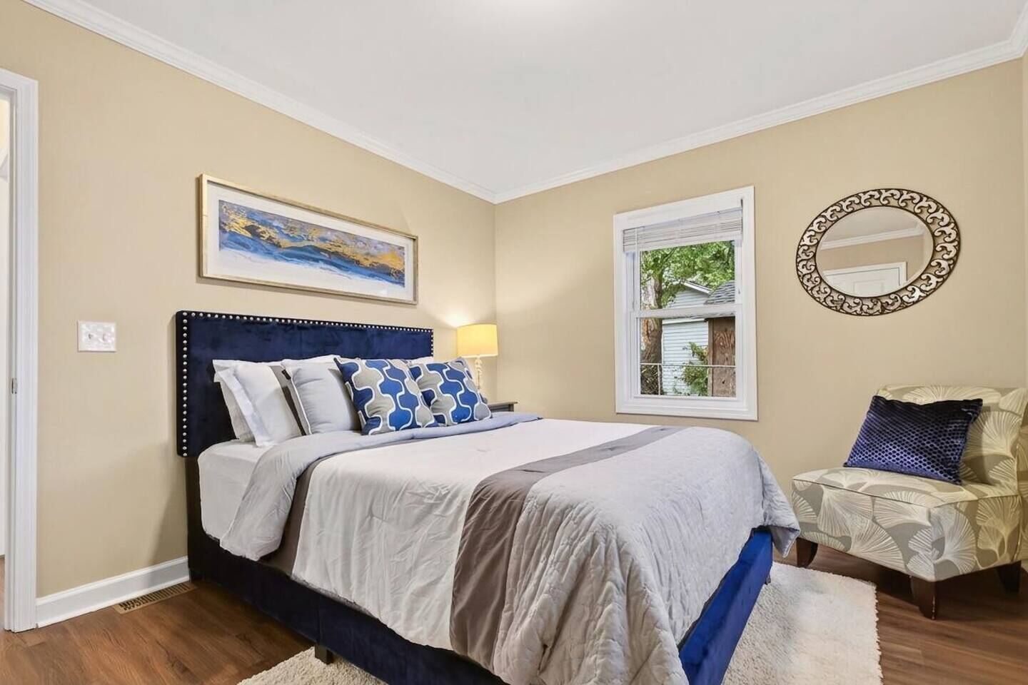 Une chambre à coucher avec un lit, une fenêtre, un tableau et un miroir.