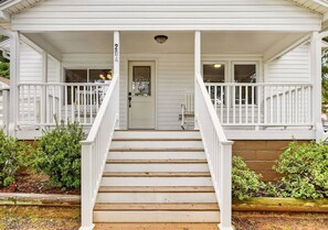 A white two-story house with a front porch, a double door, and a number '204' on the door.