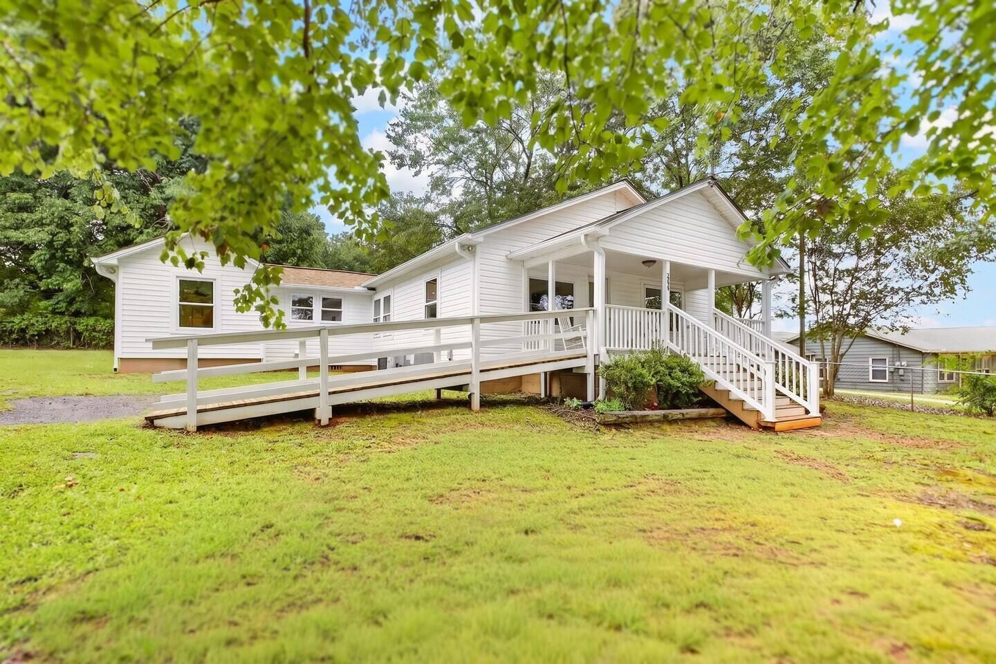 A white two-story house with a covered porch and a small staircase leading to the entrance.