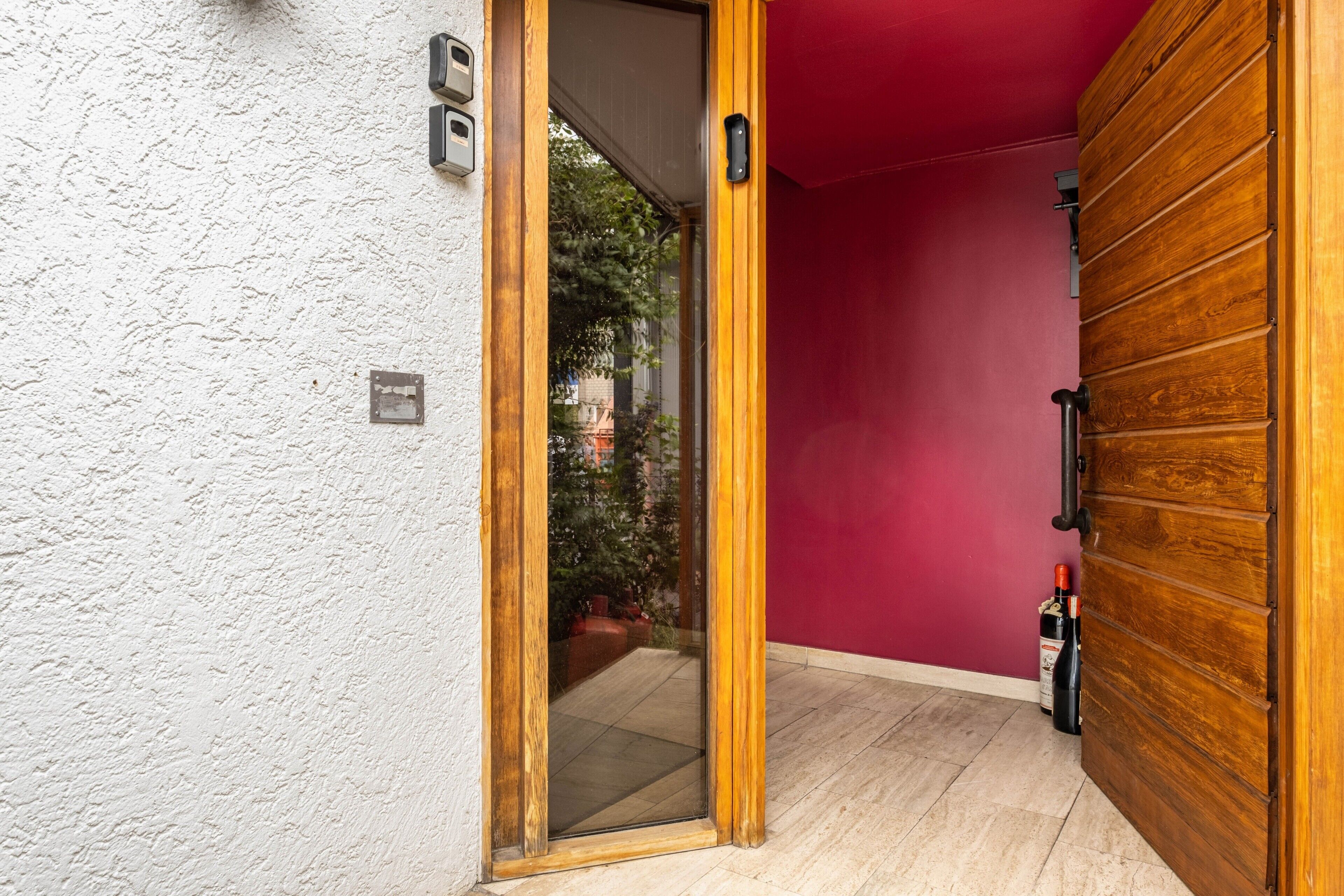 A wooden door with a glass panel, a red wall, and a tiled floor.