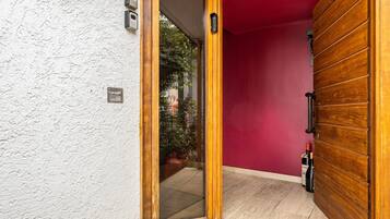 A wooden door with a glass panel, a red wall, and a tiled floor.