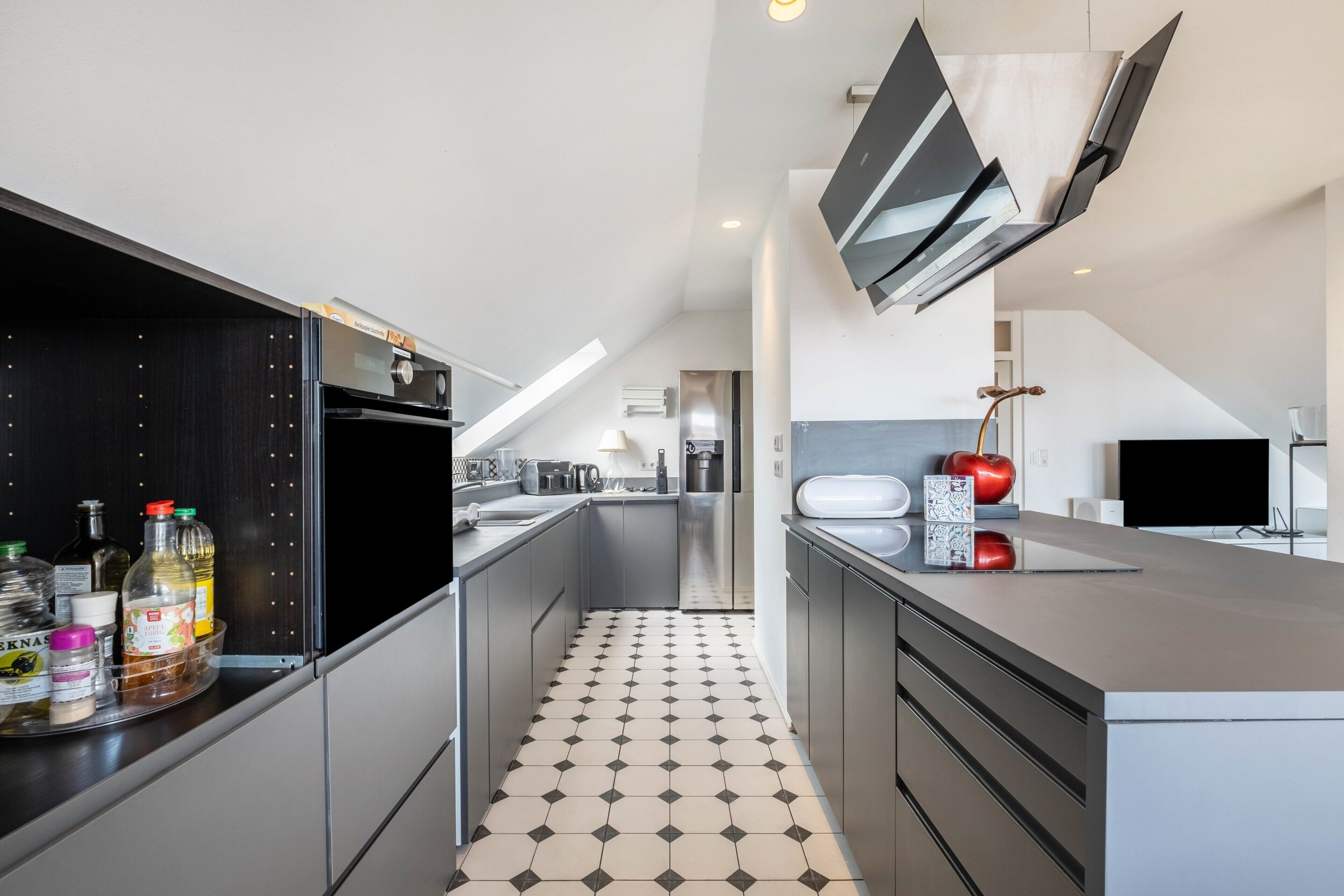 Een moderne keuken met een centraal eiland, inbouwapparatuur en een betegelde vloer.