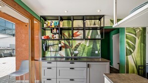 A modern kitchen with a built-in island, grey cabinetry, and a green leaf mural on the wall. - Apartment 'Loft Character' with Wi-Fi (Hofheim)