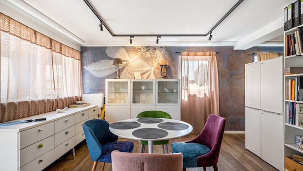 Un comedor moderno con una mesa redonda, sillas y un armario con puertas de vidrio.