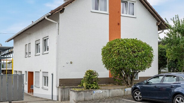 A two-story residential building with a white facade, a brown accent wall, and a small tree in front. - Apartment 'Loft Character' with Wi-Fi (Hofheim)