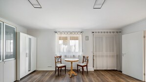 A room with a wooden floor, two chairs, a small round table, and a window with curtains. - Apartment 'Loft Character' with Wi-Fi (Hofheim)