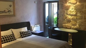 Een slaapkamer met een bed, een bureau en een stenen muur.