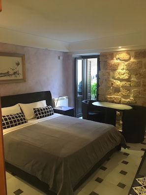 Ein Schlafzimmer mit einem Bett, einem Schreibtisch und einer Steinwand.