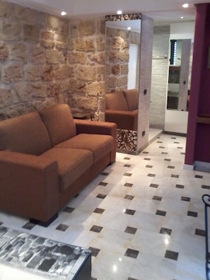 Ein Wohnzimmer mit einer Steinsäule, einem braunen Sofa und einem gemusterten Boden.