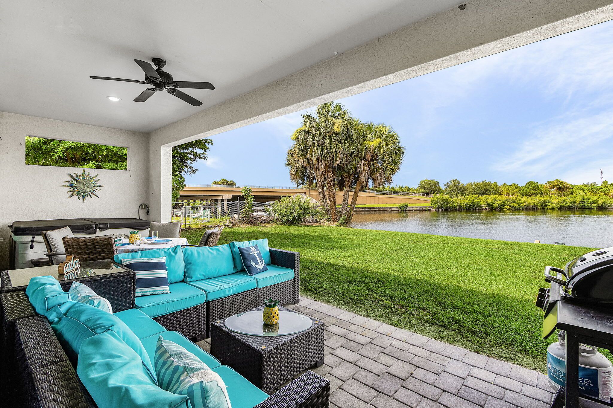 Une terrasse avec des meubles d’extérieur, un ventilateur de plafond et une vue sur un lac.