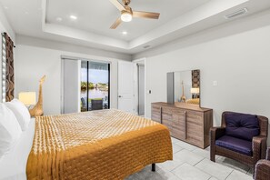 Un dormitorio con cama, ventilador de techo, cómoda y silla.