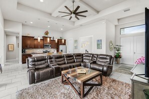 A modern living room with a sectional sofa, a coffee table, and a TV. - Spacious Waterfront Home in Cape Coral with Private Boat Slip and Hot Tub (Cape Coral)