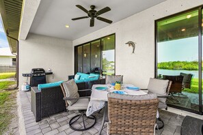 An outdoor patio with wicker furniture, a grill, and a view of a body of water. - Spacious Waterfront Home in Cape Coral with Private Boat Slip and Hot Tub (Cape Coral)