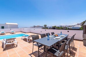 A rooftop terrace with a pool, dining table, chairs, and a view of the cityscape. - Villa Camino del Volcan by Villa Plus (Mácher)