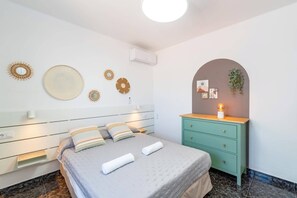 A bedroom with a bed, a dresser, wall decor, and an air conditioning unit. - Villa Camino del Volcan by Villa Plus (Mácher)