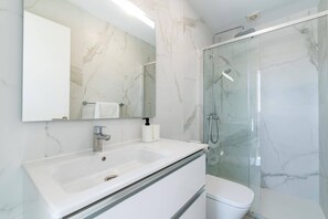 Une salle de bain avec un lavabo en marbre, des toilettes et une douche à parois de verre.