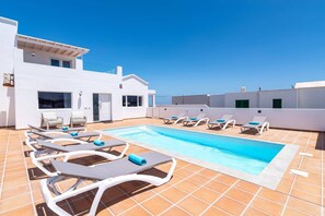 Un espace piscine aménagé sur le toit, avec des chaises longues et une piscine.