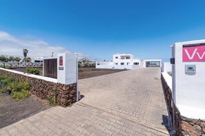 Un chemin pavé mène à un bâtiment blanc, avec une montagne en arrière-plan.