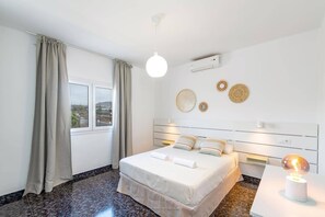 A hotel room with a bed, curtains, a window, wall decorations, and a ceiling light. - Villa Camino del Volcan by Villa Plus (Mácher)